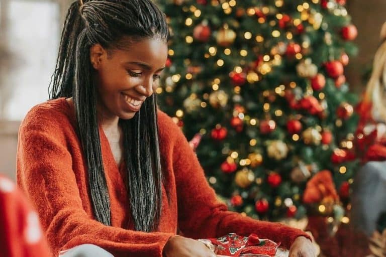 Black woman in red sweater in front of christmas tree