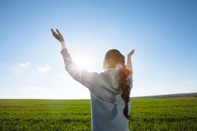 Woman standing with hands up to sky with encourage yourself in the lord scripture